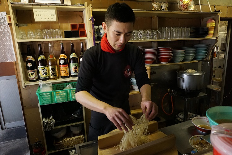 3代目店主の山路重紀さん。木蓋の上で麺をほぐしてから釜に落とす。伝統のスタイルを守りながら“より旨い一杯”を日々研究