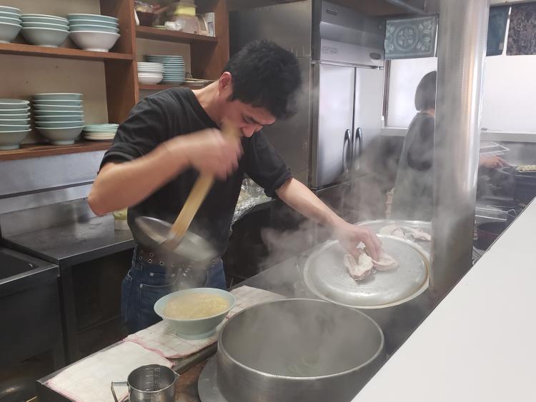 店主の小畑登さん。昔ながらの平網で湯切りする