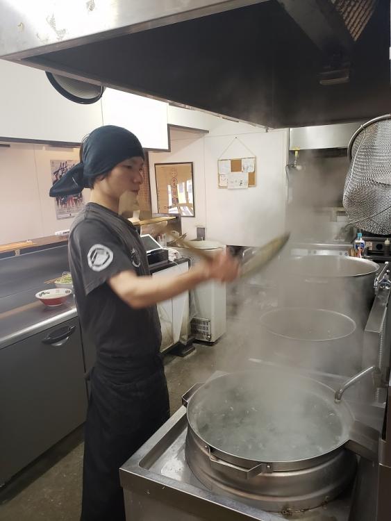 大釜で自家製麺を泳がし、緩やかなカーブのザルで湯切りする。腕を高く上げるのが龍之介スタイル